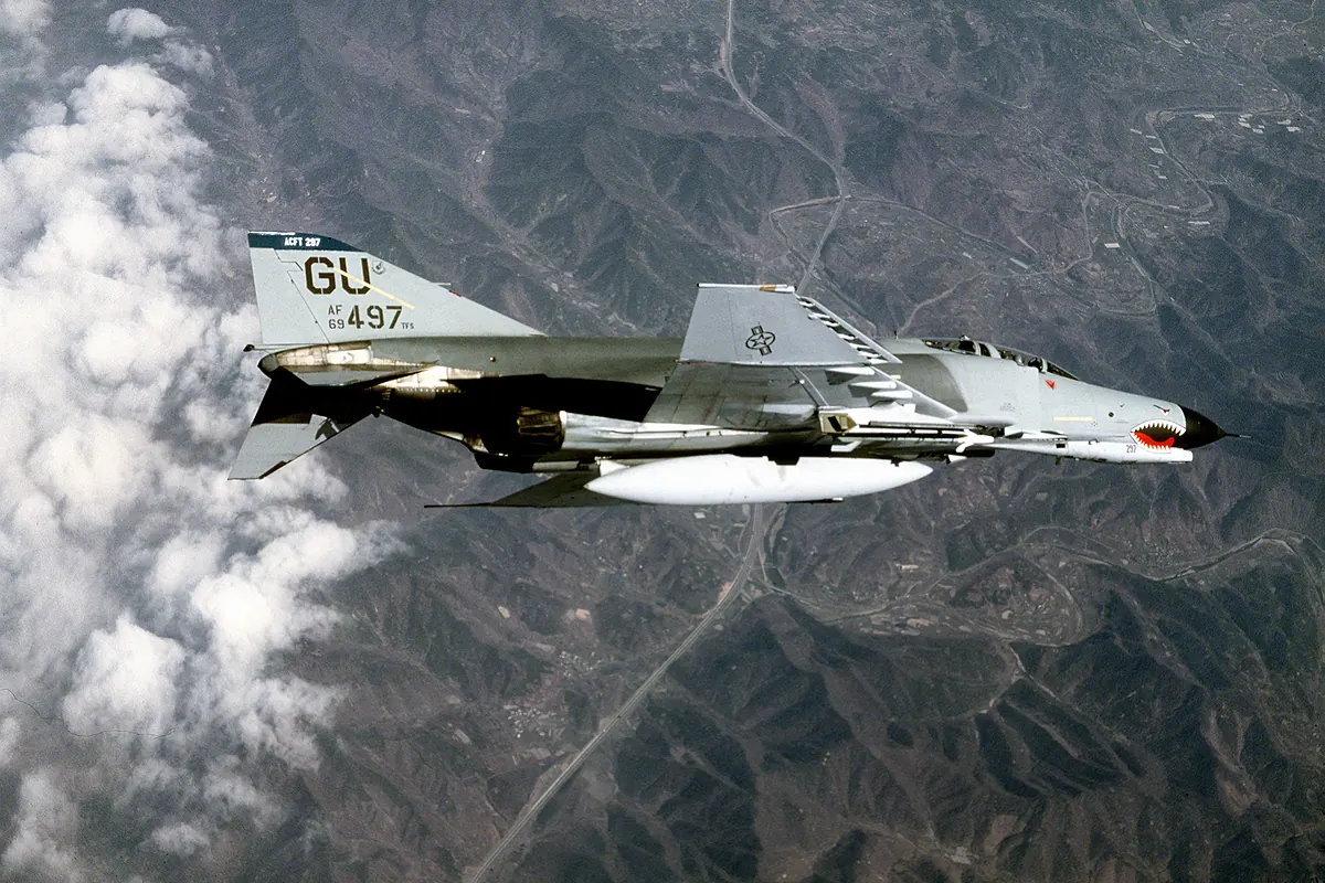 F-4E Phantom II amerického letectva v šedé kamufláži se žraločí tlamou na přídi nad horami Jižní Koreje, 1986